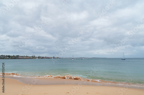 Sandy ocean beach with soft waves and yachts in the lagoon © Olga K