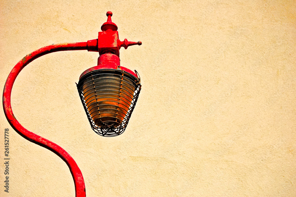 Obraz premium Rusty cast iron street lamp against cream painted textured wall