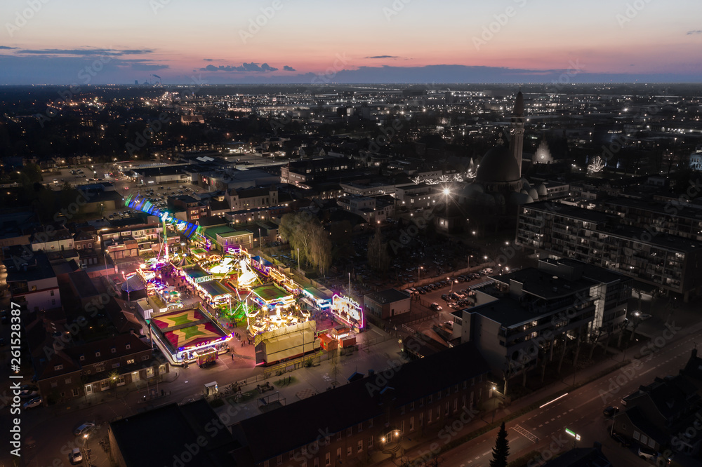 Fototapeta premium Waalwijk, Noord Brabant, Netherlands - april 12 2019: fairground with thrill rides. Fair on a square in the city center, seen from above at night.