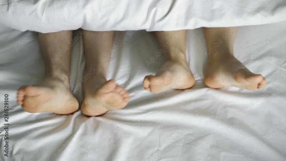 A pair of legs dancing under a white blanket, on a white bed, top view.4k A pair of legs dancing under a white blanket, on a white bed, top view.4k