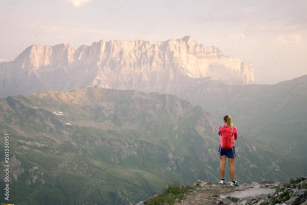 Fototapeta premium A hiker enjoying the view of sunsrise over the mountains and valleys of the Alps in summer.