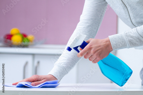 Dusting and polish furniture using cleaning products at kitchen home. Housekeeping, household chores.