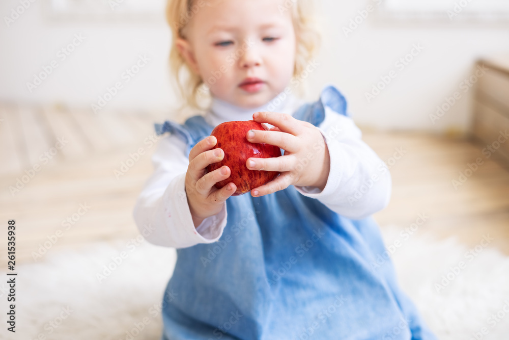 Children with fruits: A two-year-old little girl in a blue sundress holds a big red apple. Children with fruits: A two-year-old little girl in a blue sundress holds a big red apple.