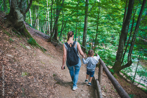 mother with son walking forest trail holding hands