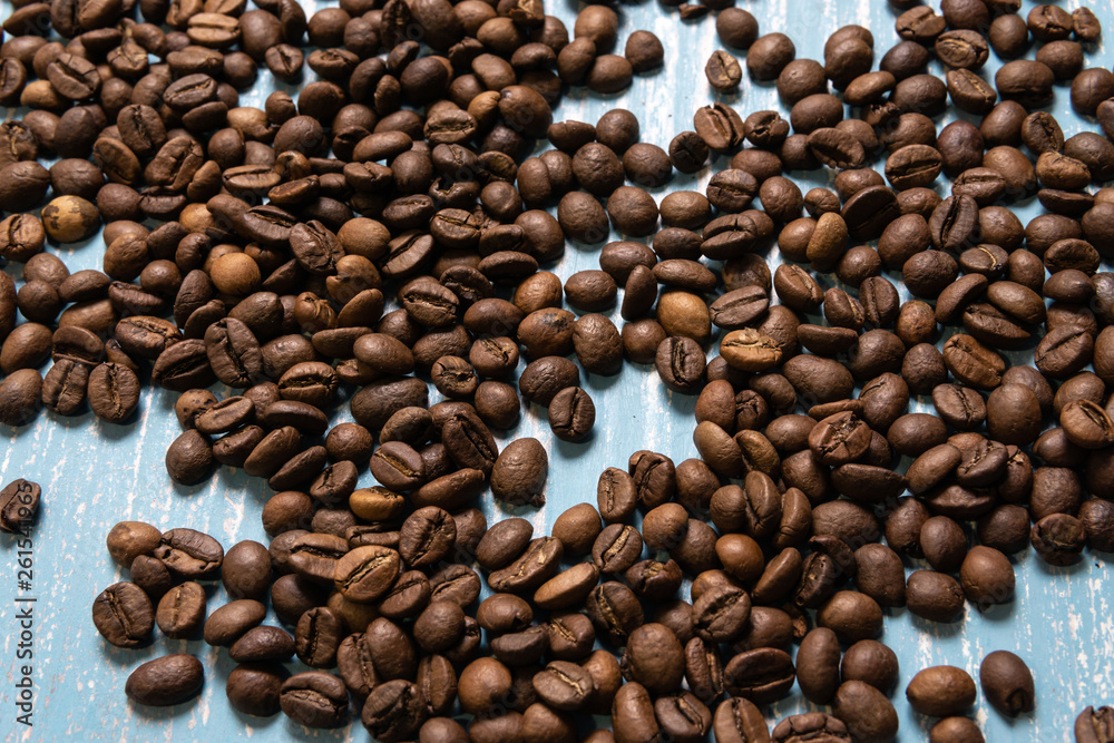 Obraz premium Roasted coffee beans in bulk on a blue wooden background