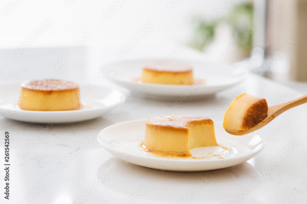 A bite piece of sweet creamy caramel custard in spoon and in plate A bite piece of sweet creamy caramel custard in spoon and in plate