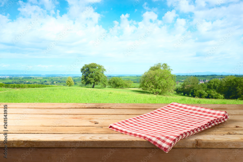 Empty wooden table with tablecloth over summer meadow background - obrazy, fototapety, plakaty 