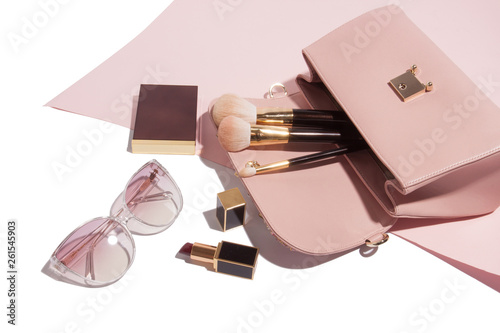 Layout of female coral pink leather handbag stuff of make up brushes