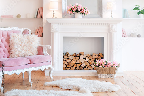 Modern light interior with fireplace, spring flowers and cozy pink sofa