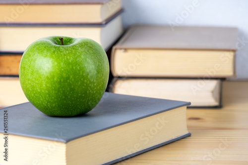 books and green apple on the wooden table