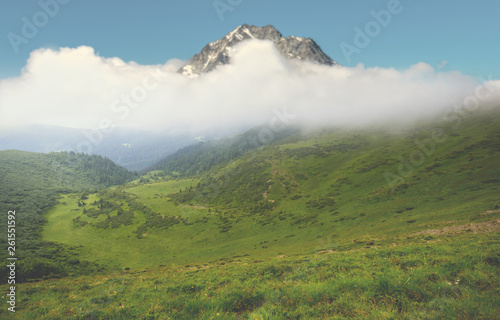 high mount top in a dense clouds over the green mountain valley