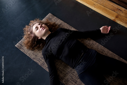 woman practicing in a yoga studio resting in shavasana or corps pose photo