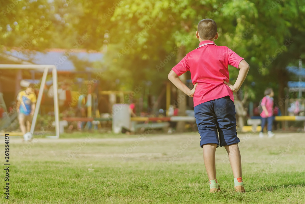 Asian boys practice kicking the ball to score goals in the public football field.