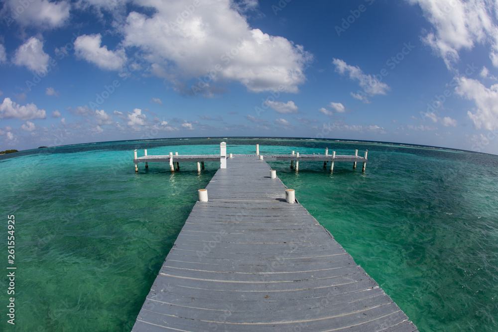 A jetty reaches out into the calm lagoon in Turneffe Atoll, Belize. This area, not far from the famous Blue Hole, is known for its beautiful scuba diving and snorkeling.