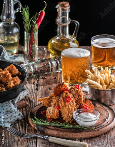 chicken wings in a batter with beer and fries on a wooden plate with sauce