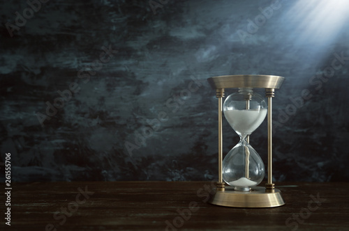 Hourglass as time passing concept in front of black wall background. Conceptual photo on history, fantasy and education