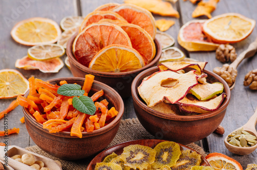 Mixed dried fruit chips, candied pumpkin slices, nuts and seeds on rustic wooden background