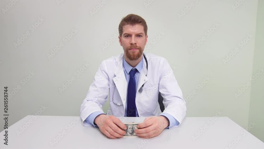 Doctor showing bundle of money looking at the camera and smiling Doctor showing bundle of money looking at the camera and smiling