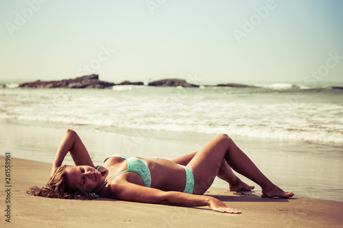 Young woman is lying on the beach against the background of sea and stones