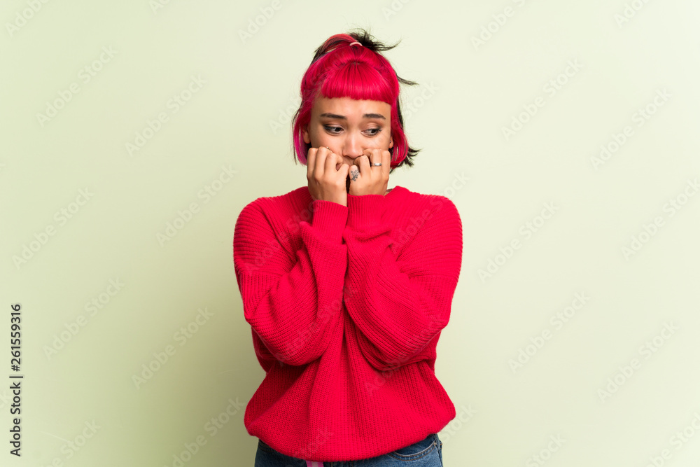 Young woman with red sweater is a little bit nervous and scared putting hands to mouth