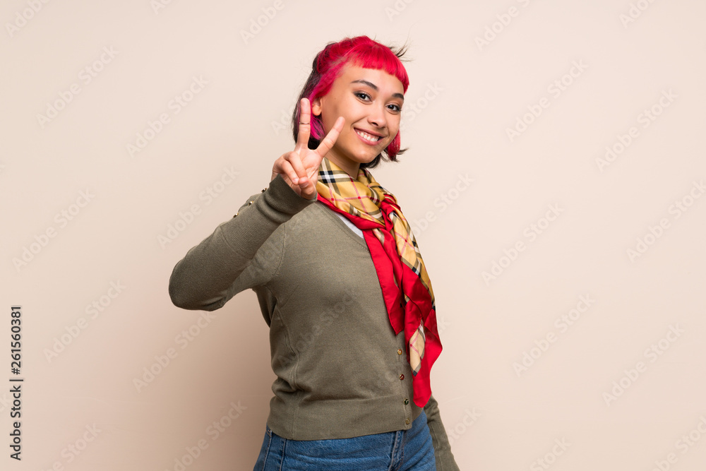 Young woman with pink hair over yellow wall smiling and showing victory sign Young woman with pink hair over yellow wall smiling and showing victory sign