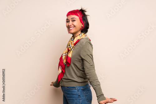 Young woman with pink hair over yellow wall smiling