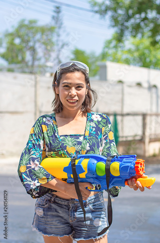 Asian woman holding a water gun play Songkran festival or Thai new year in Thailand.