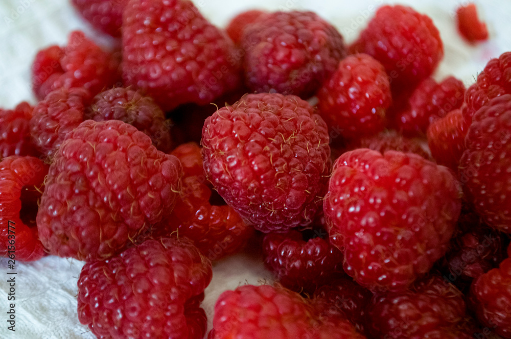 Big ripe raspberries are laying on the table covered with white tablecloth Big ripe raspberries are laying on the table covered with white tablecloth