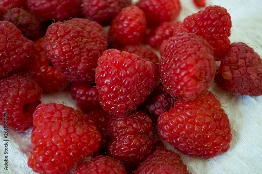 Big ripe raspberries are laying on the table covered with white tablecloth Big ripe raspberries are laying on the table covered with white tablecloth