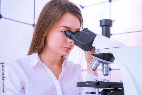 Young woman technician is examining a histological sample  a biopsy in the laboratory of cancer research