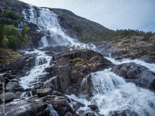 Langfossen waterfall at its splendid. Vast and tall waterfall  flowing around the rocks and in between the trees. Immense power of the nature. The water falls down a towering mountain  612meters.