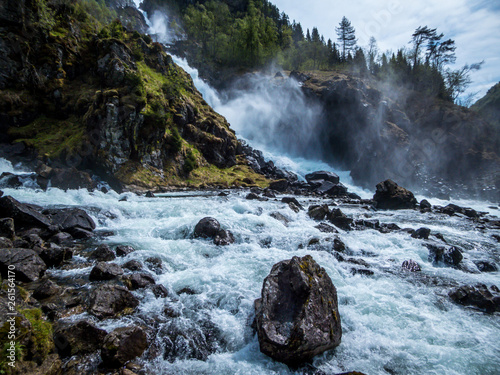 Lower parts of Langfossen waterfall at its splendid. Vast and tall waterfall, flowing around the rocks and in between the trees. Immense power of the nature. The water falls down a towering mountain photo