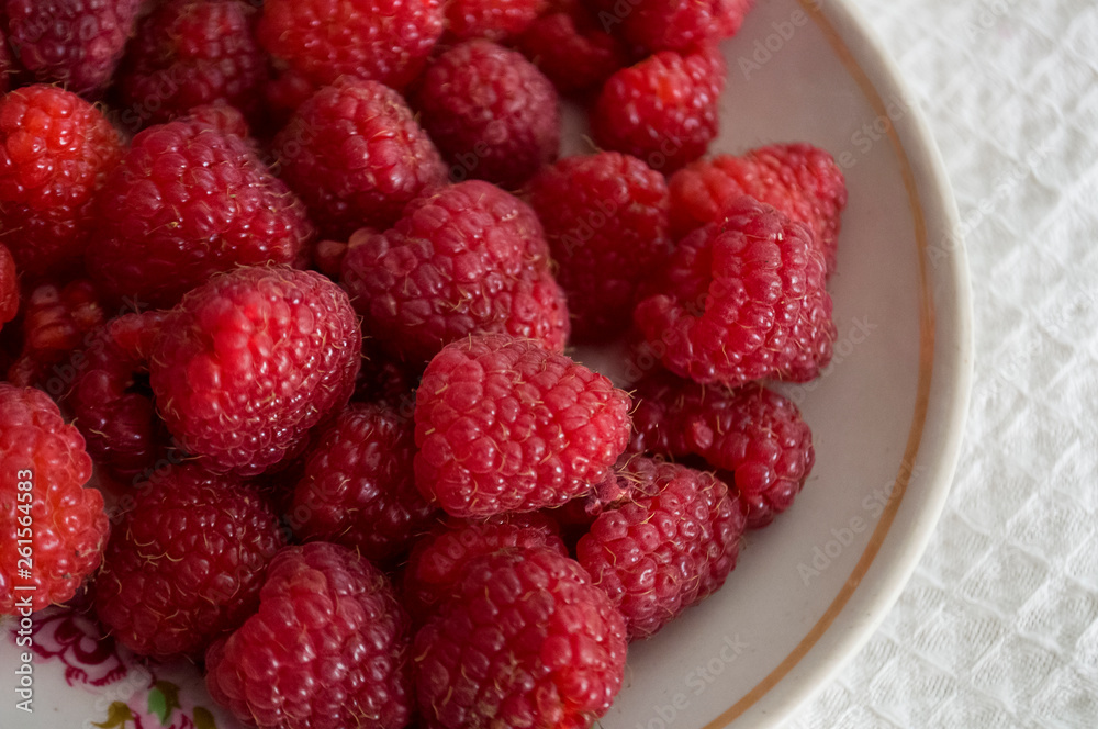 Big ripe raspberries are laying on the table covered with white tablecloth Big ripe raspberries are laying on the table covered with white tablecloth