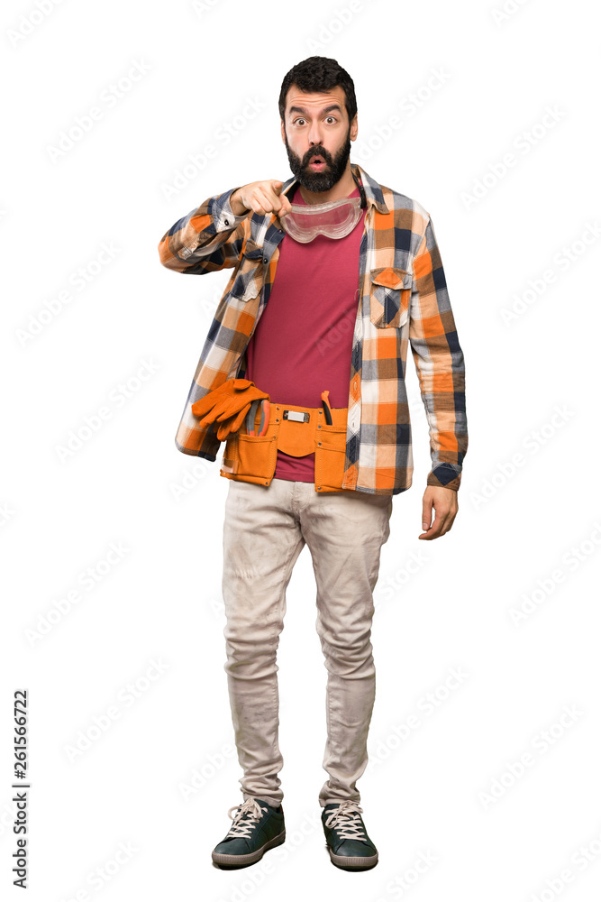 Craftsmen man surprised and pointing front over isolated white background Craftsmen man surprised and pointing front over isolated white background