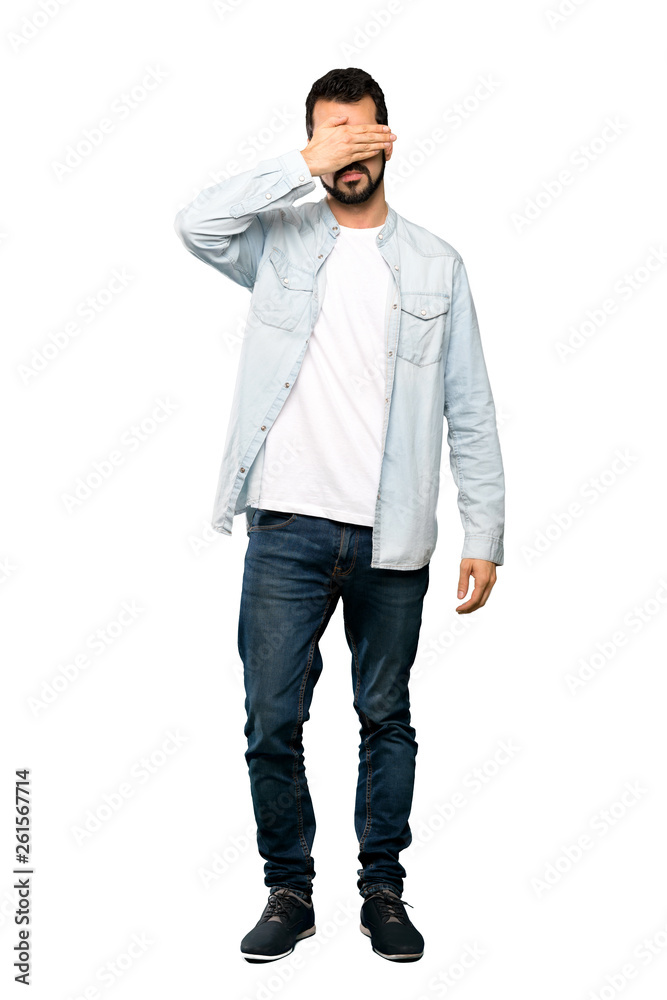 Full-length shot of Handsome man with beard covering eyes by hands. Do not want to see something over isolated white background Full-length shot of Handsome man with beard covering eyes by hands. Do not want to see something over isolated white background