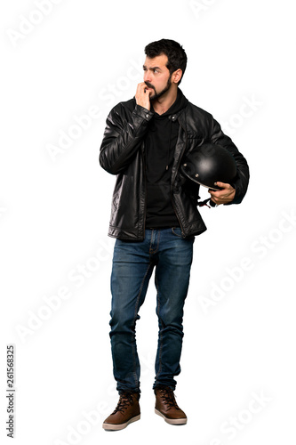 Full-length shot of Biker man nervous and scared putting hands to mouth over isolated white background