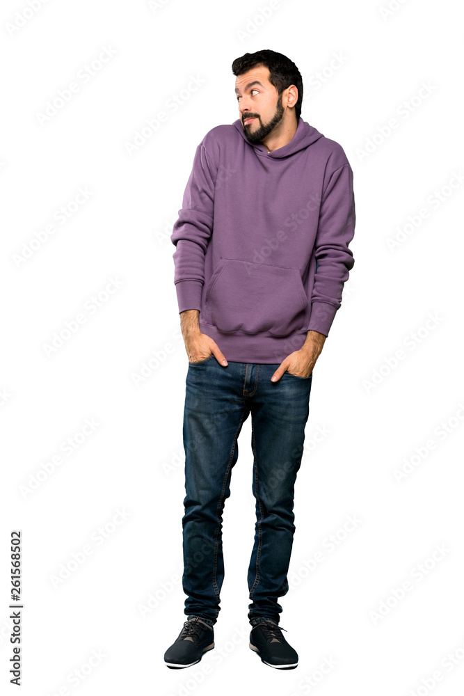 Full-length shot of Handsome man with sweatshirt making doubts gesture looking side over isolated white background Full-length shot of Handsome man with sweatshirt making doubts gesture looking side over isolated white background