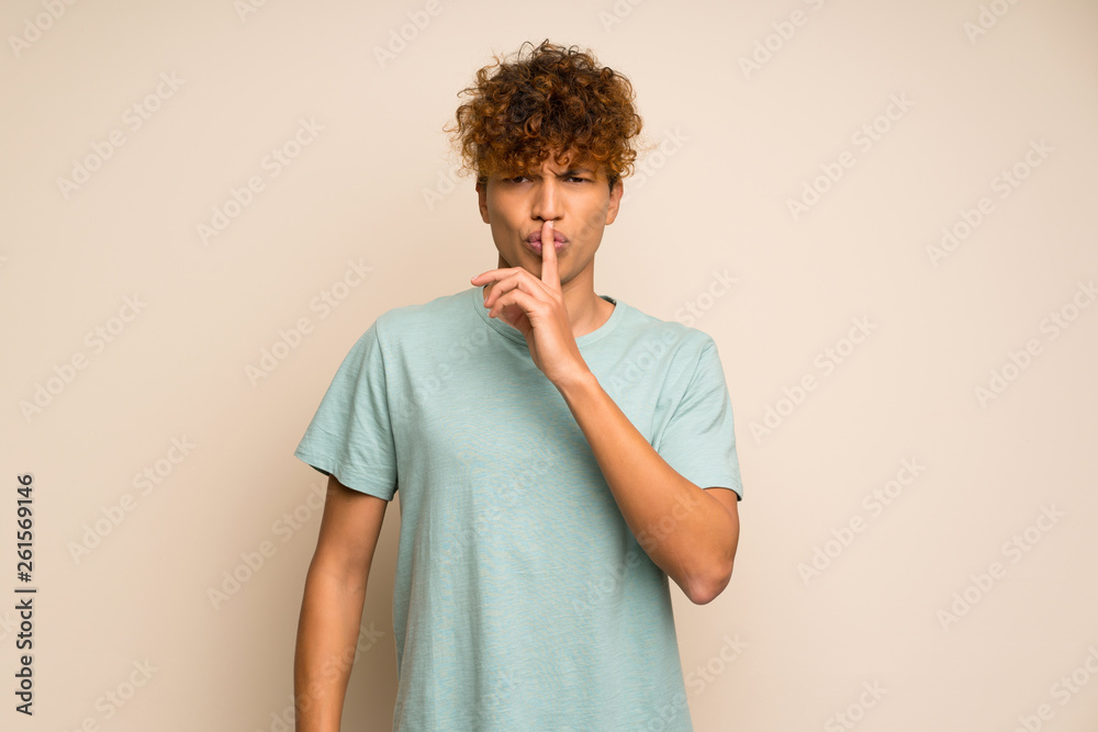 African american man with green shirt showing a sign of silence gesture putting finger in mouth African american man with green shirt showing a sign of silence gesture putting finger in mouth