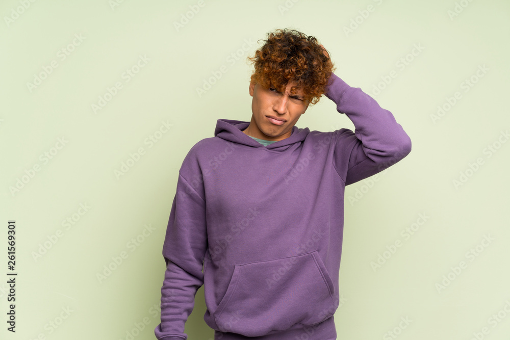 Young african american man over isolated green wall with an expression of frustration and not understanding Young african american man over isolated green wall with an expression of frustration and not understanding