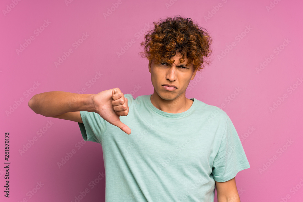 Young african american man over isolated purple wall showing thumb down sign Young african american man over isolated purple wall showing thumb down sign