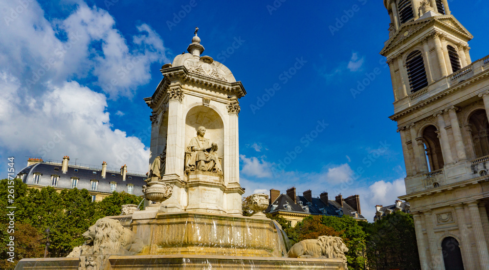 Fountain in front of the church of Saint-Sulpice in cloudy blue sky day in Paris, France
