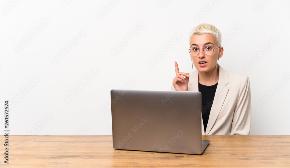 Teenager girl with short hair with a laptop thinking an idea pointing the finger up Teenager girl with short hair with a laptop thinking an idea pointing the finger up