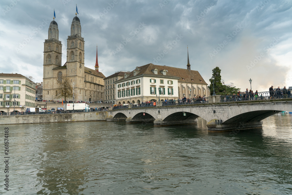 Fototapeta premium Zurich cityscape with many people crossing the river Limmat during the traditional spring festival of Sechselauten in April