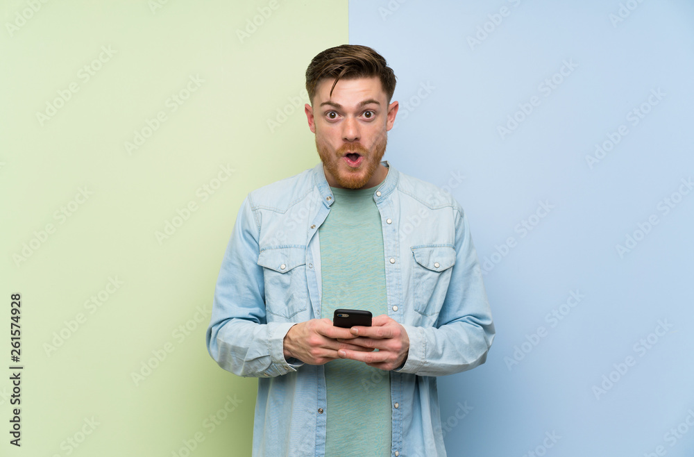 Redhead man over colorful background surprised and sending a message Redhead man over colorful background surprised and sending a message
