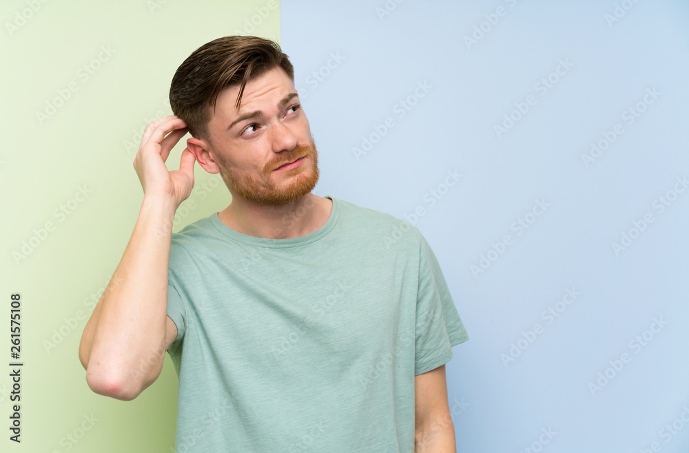 Redhead man over colorful background having doubts and with confuse face expression Redhead man over colorful background having doubts and with confuse face expression