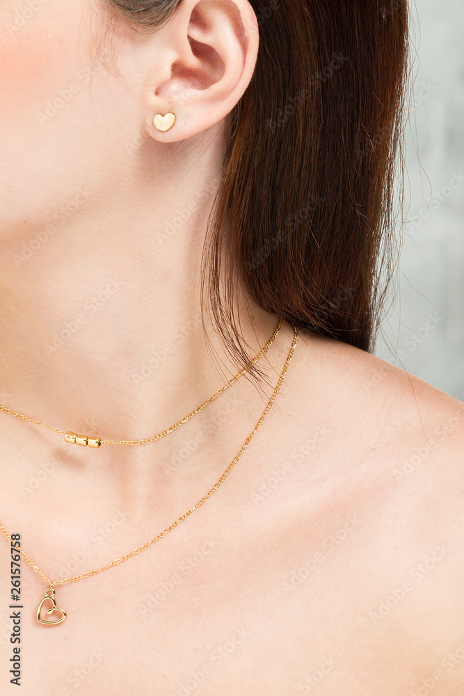 Oreja de mujer con aretes oro, pelo caótico y piel suave Stock Photo