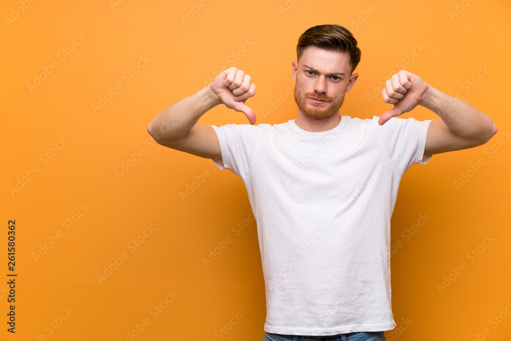 Redhead man over brown wall showing thumb down Redhead man over brown wall showing thumb down