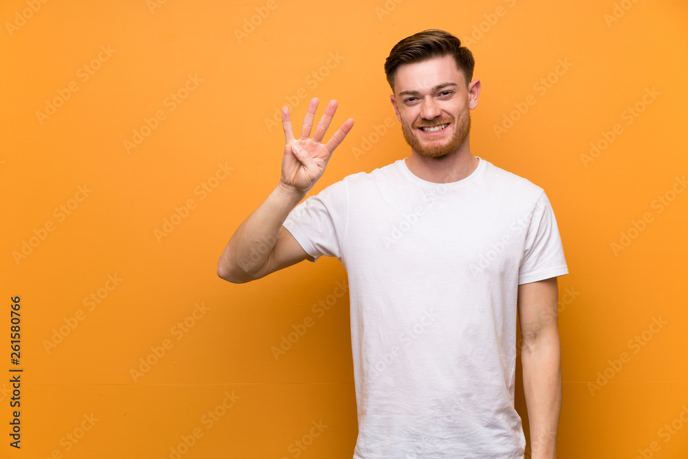 Redhead man over brown wall happy and counting four with fingers Redhead man over brown wall happy and counting four with fingers