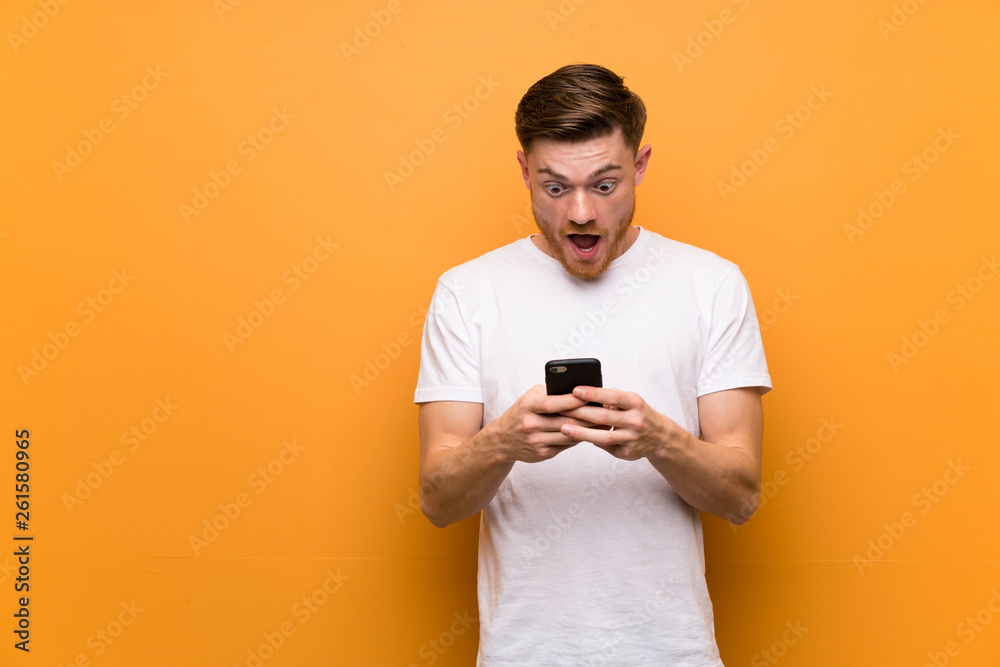 Redhead man over brown wall surprised and sending a message Redhead man over brown wall surprised and sending a message