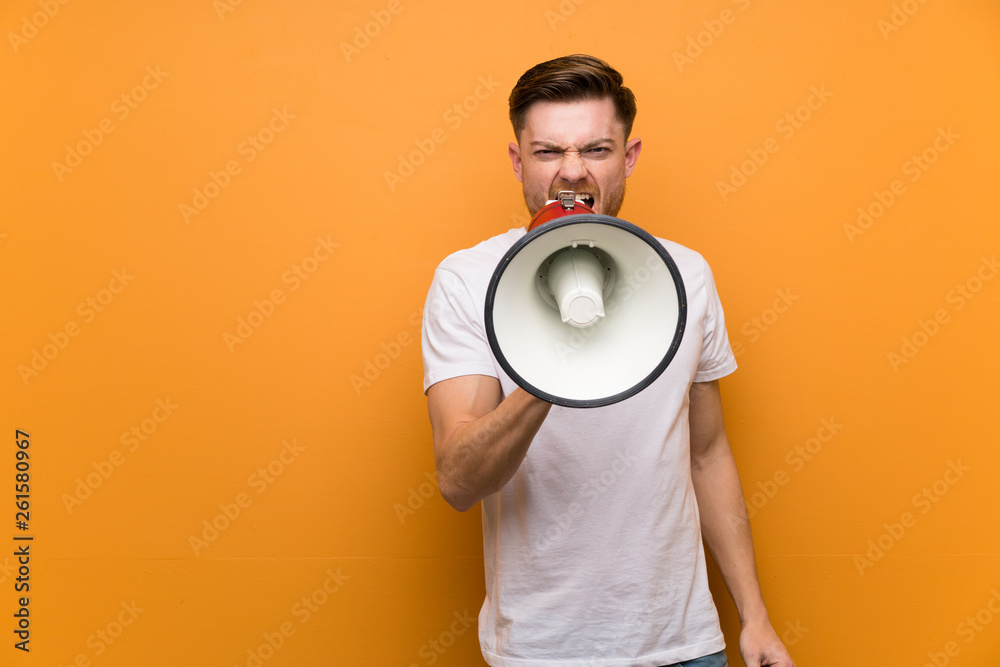 Redhead man over brown wall shouting through a megaphone Redhead man over brown wall shouting through a megaphone